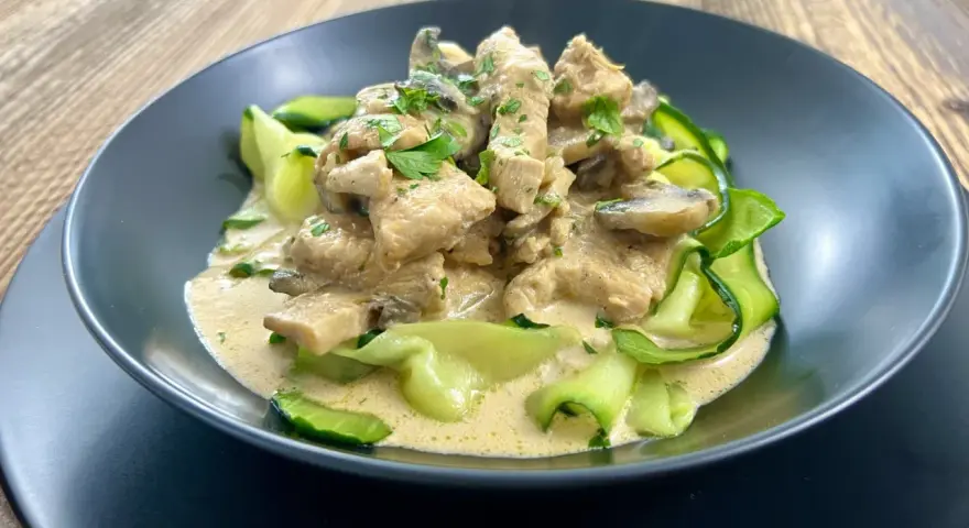 Pyszny keto obiad z kurczakiem w kremowym sosie z pieczarkami, podany z makaronem z cukinii.