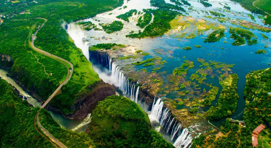 Wodospad Wiktorii, jedna z największych atrakcji Zimbabwe, z lotu ptaka. Potężny nurt rzeki Zambezi spada kaskadami w dół, tworząc mgłę i tęczę.