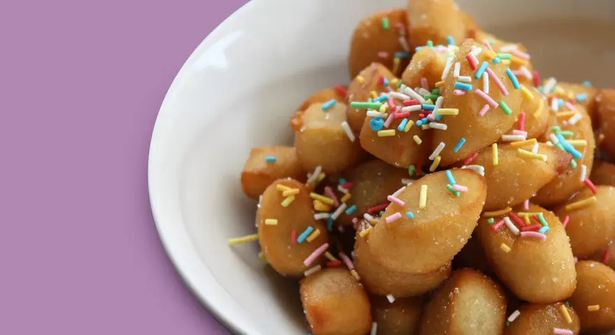 Un piatto di dolci tipici pugliesi, piccole palline dorate cosparse di zuccherini colorati, invitano a un assaggio di tradizione.