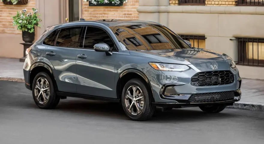 Elegancki, szary SUV Honda HR-V stoi na ulicy przed budynkiem z cegły.