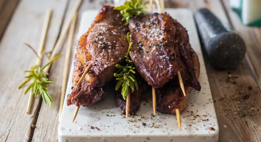 Brochettes de magret de canard marinées, garnies de romarin frais et saupoudrées de gros sel. Un délice à partager.