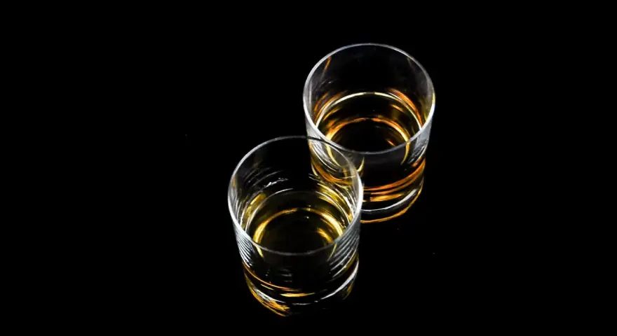 Dwa szklanki z bursztynowym płynem, idealne na wieczór z drinkiem. Czy to Baileys?