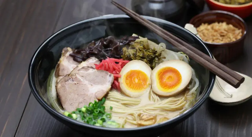 Pyszny ramen co to? Aromatyczny bulion, makaron, plastry wieprzowiny, jajko na pół, szczypiorek i marynowane dodatki.