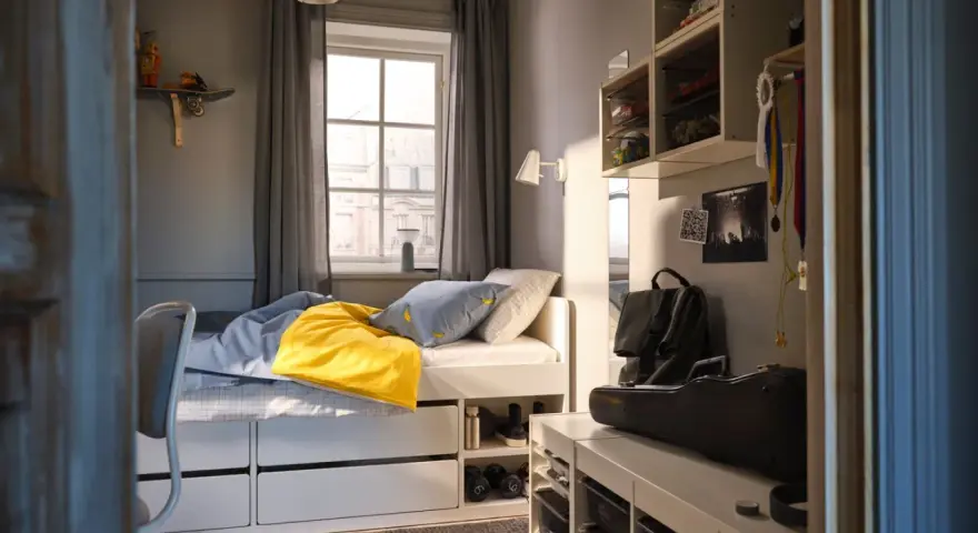 Ett mysigt tonårsrum kille med säng, skrivbord och förvaring. En gul filt och banankudde piggar upp.