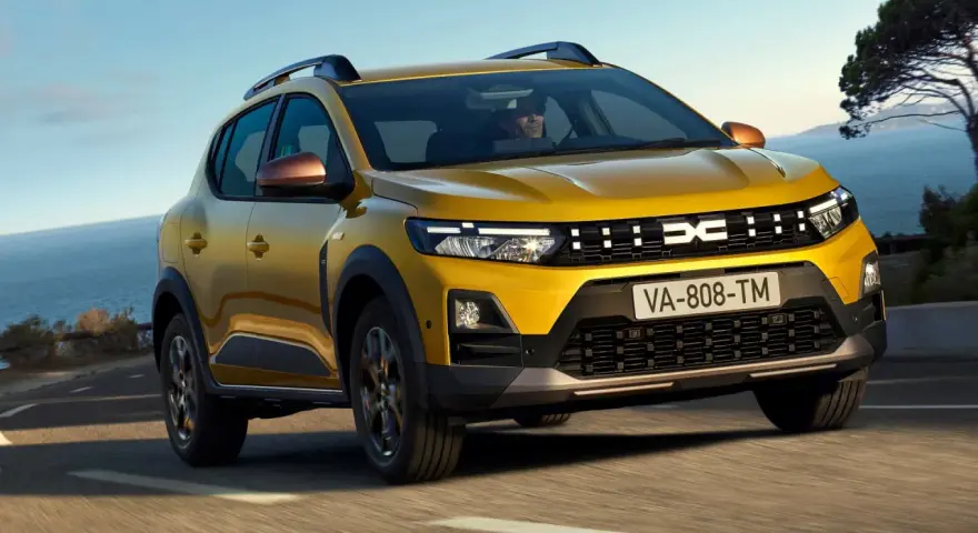 Żółty Dacia Duster, jeden z wielu popularnych dacia modele, jedzie po krętej drodze nad morzem.