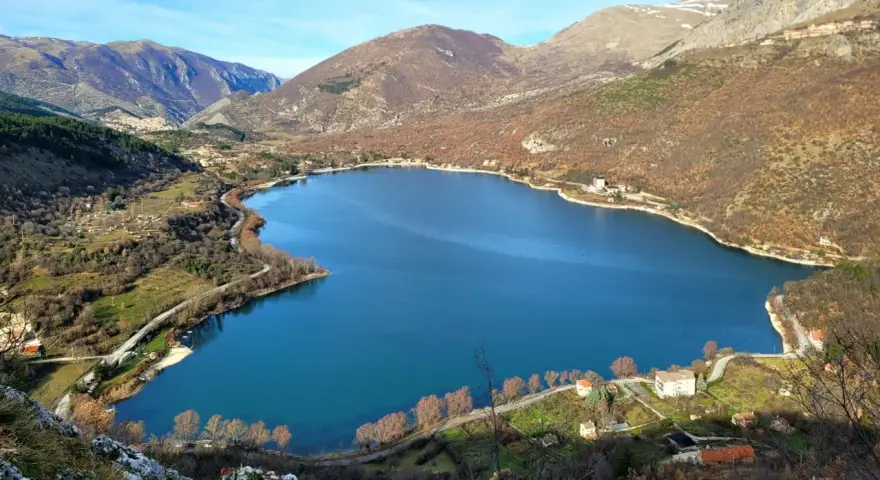 Panoramica del lago di Scanno, con montagne sullo sfondo e case sparse lungo la riva. Un luogo incantevole da esplorare.