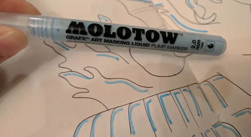 A hand holds a light blue Molotow Grafx Art Masking Liquid Pump Marker over a drawing.