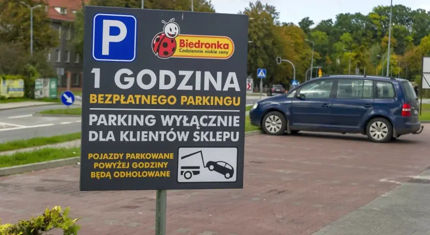 Tablica informuje o 1 godzinie darmowego parkingu dla klientów Biedronki. Pojazdy parkowane dłużej mogą otrzymać mandat za parkowanie i zostać odholowane.