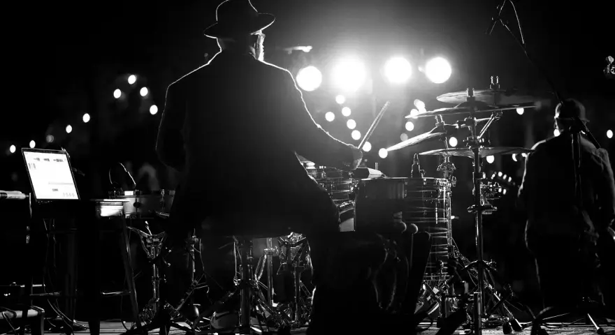 Perkusista w kapeluszu gra na bębnach podczas koncertu MTV Unplugged Polska.