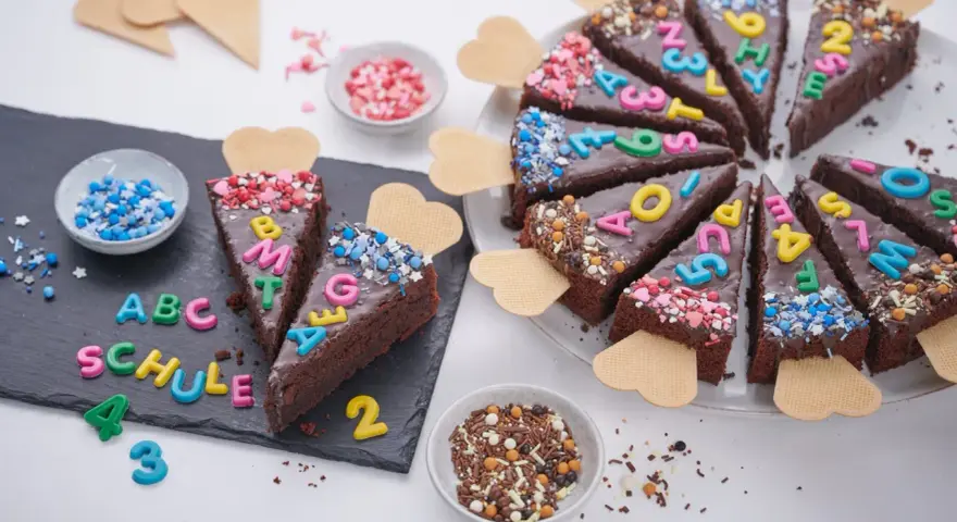 Schokoladenkuchenstücke mit bunten Buchstaben und Zahlen, die "ABC SCHULE" ergeben. Ein perfekter Kuchen zur Einschulung!