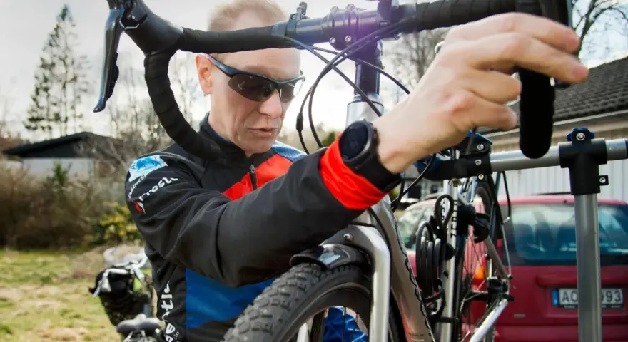 Man i cykelkläder fokuserar på att laga punktering på sin cykel.