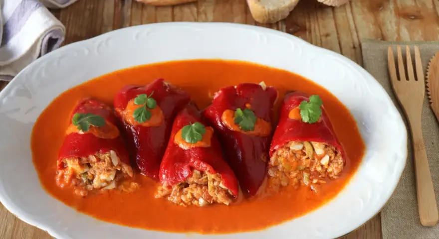 Pimientos del piquillo rellenos de atún y huevo, servidos en una salsa roja cremosa.