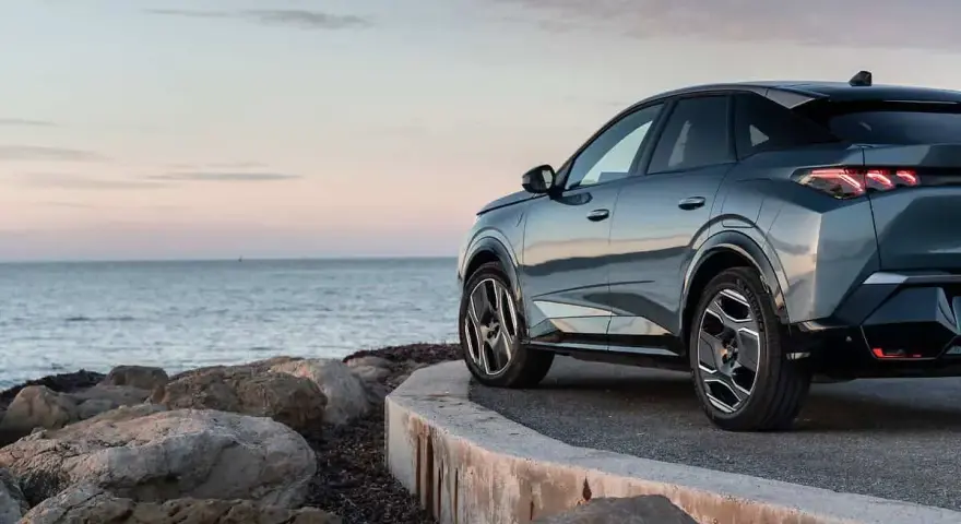 Nowy Peugeot 3008 hybryda na tle spokojnego morza i skalistego wybrzeża.