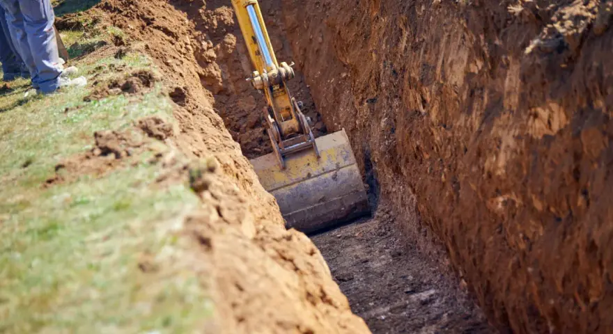 Koparka pogłębia wykop pod garaż. Widać jaki głęboki fundament pod garaż powstaje.