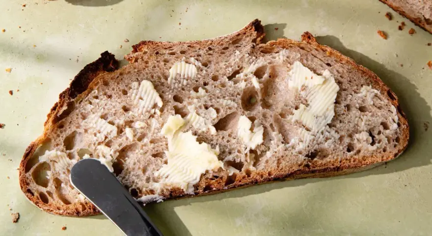 Tranche de pain de campagne, généreusement beurrée, prête à être dégustée. Une invitation à la simplicité et au bon goût.