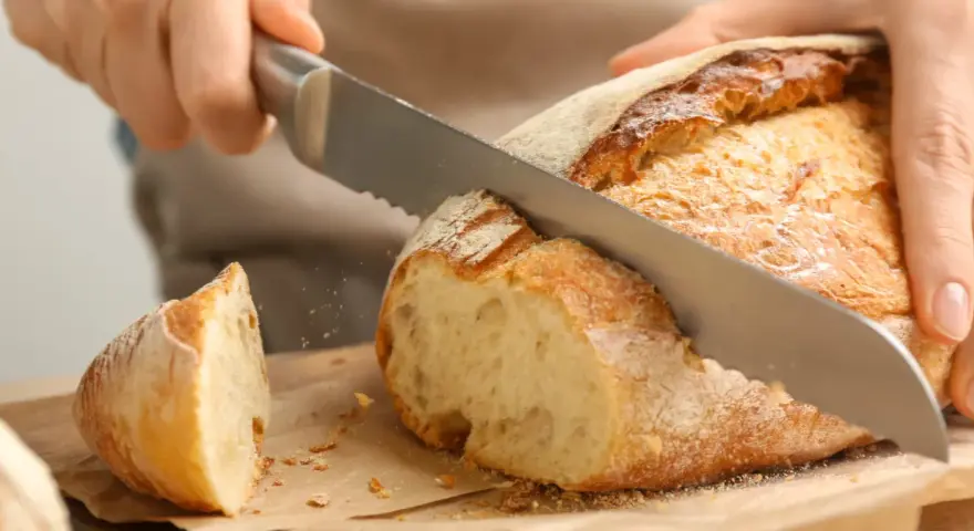 Krojenie świeżo upieczonego, domowego chleba. Ten przepis na chleb domowy pieczony w piekarniku jest idealny na każdą okazję.