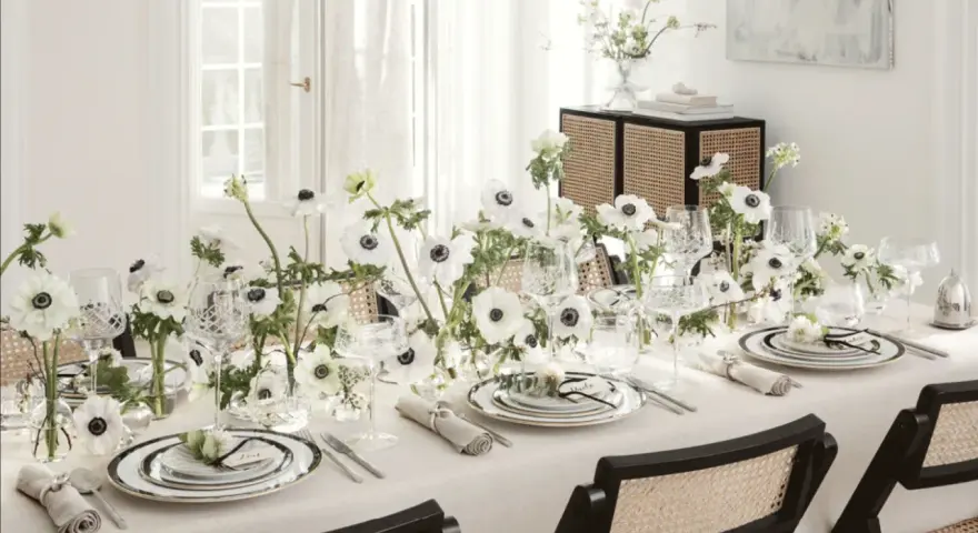 Ett elegant dukat bord med vita anemoneblommor och kristallglas. En diskret detalj är sugrör guld som ger en lyxig touch.