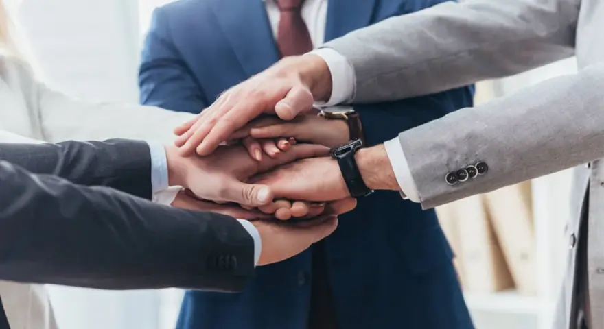 Zespół składa dłonie, symbolizując jedność i siłę. To jak prokura samoistna – wspólne działanie dla dobra firmy.