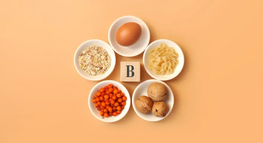En ägg, havregryn, pasta, havtorn och valnötter arrangerade runt en träkub med bokstaven B, som symboliserar alla b-vitaminer.