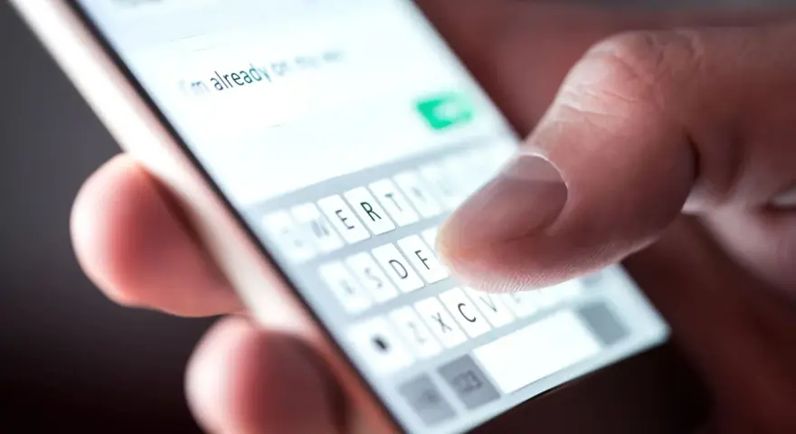 Pisanie wiadomości: "Dziękuję za zaproszenie, potwierdzam przybycie!" na ekranie telefonu.