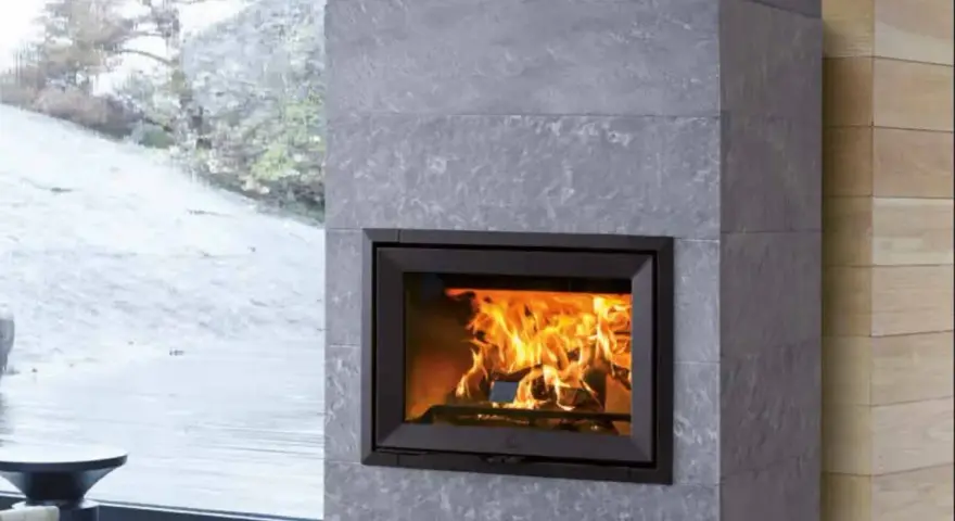 Chimenea moderna de piedra gris con fuego crepitante. Es hora de insertarleña para mantener el calor.