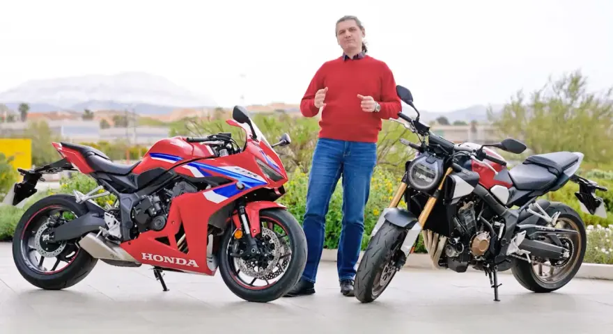 Mężczyzna w czerwonym swetrze prezentuje dwa motocykle Honda: sportowy CBR i naked bike CB650R.