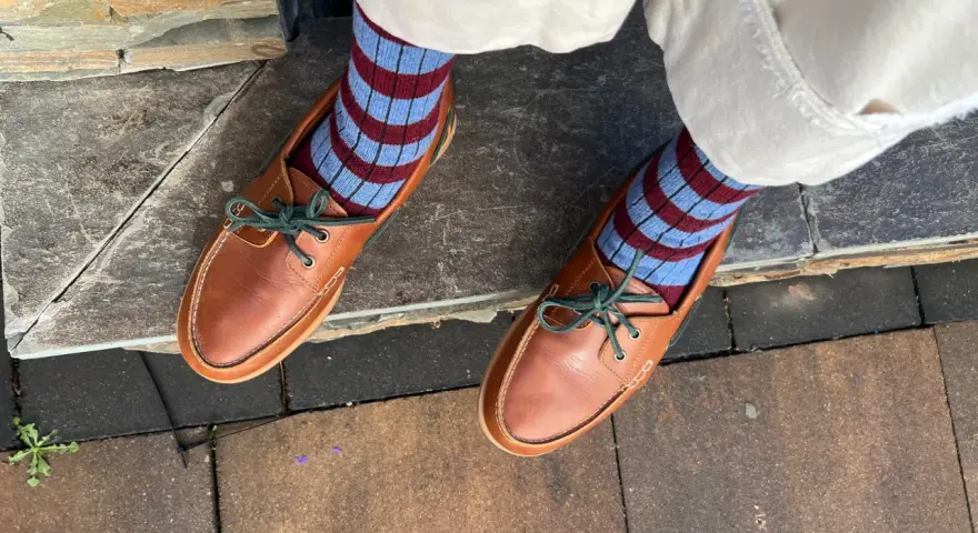 Pies con calcetines a rayas azul y burdeos y mocasines de cuero marrón. Un ejemplo de cómo combinar color teja ropa con estilo.