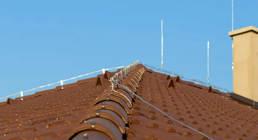 Nowy dach z brązowej dachówki, na którym zamontowano nowoczesną instalację odgromową, chroniącą przed burzami.