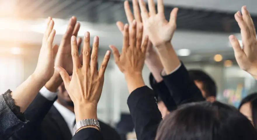 Des mains levées en signe de victoire, célébrant un succès collectif. L'équipe est unie, prête pour le quitus au syndic.