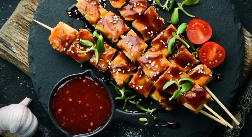 Hähnchenspieße mit glänzender Teriyaki-Sauce, Sesam und Kirschtomaten. Ein köstliches teriyaki sauce rezept zum Nachmachen.