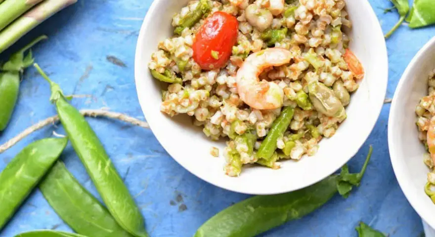 Deliziosa insalata di cereali con gamberetti, pomodorini, asparagi e fave. Un piatto fresco e nutriente.