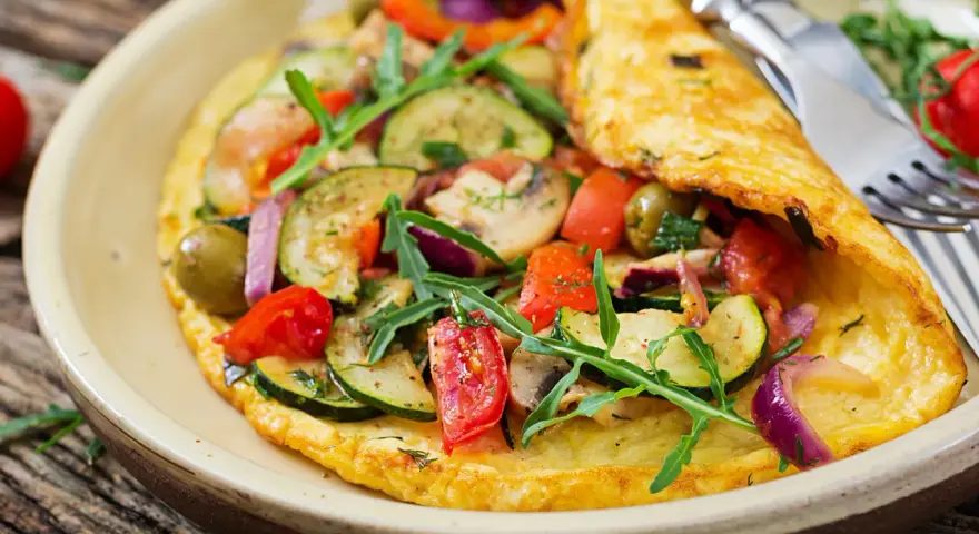 Puszysty omlet dla niemowlaka z cukinią, pomidorkami, oliwkami i rukolą. Zdrowy i kolorowy posiłek.