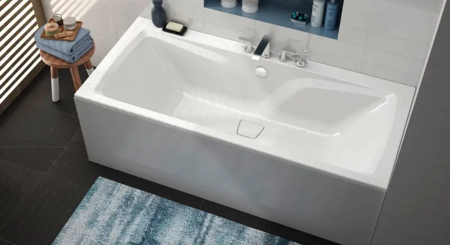 Baignoire blanche moderne, d'une largeur baignoire standard, avec robinetterie chromée et étagère murale.