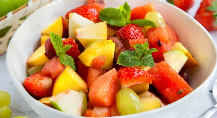 Ein bunter Obstsalat mit Erdbeeren, Melone, Pfirsich und Trauben – ein einfaches obstsalat rezept für heiße Tage.