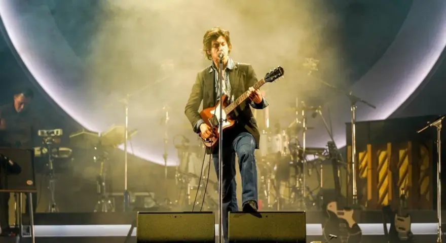 Alex Turner z Arctic Monkeys Polska na scenie, grając na gitarze w otoczeniu dymu i świateł.