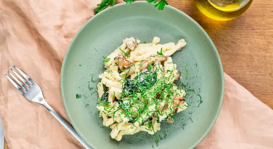Krämig svamp pasta med färska örter på en grön tallrik, redo att avnjutas.