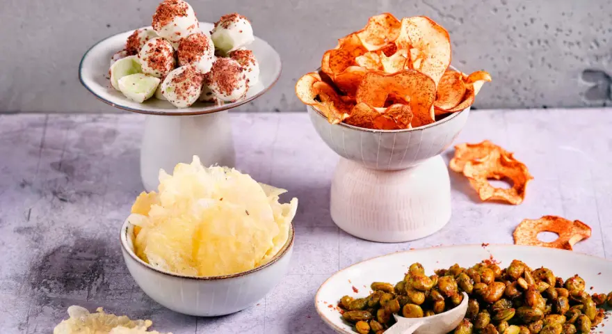Leckere filmabend snacks: weiße Schoko-Bällchen, Apfelchips, knusprige Cracker und gewürzte Edamame.