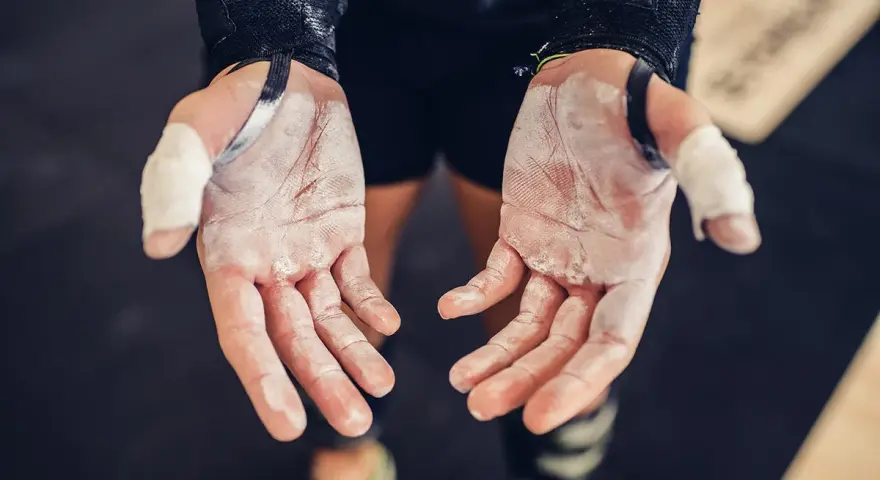 Mains de sportif couvertes de magnésie, témoignant d'une main calleuse et d'un entraînement acharné.