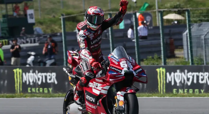 Piloto de MotoGP celebra victoria en su moto Ducati roja. Aunque no se especifica cuanto mide Marc Márquez, su presencia en la pista es imponente.