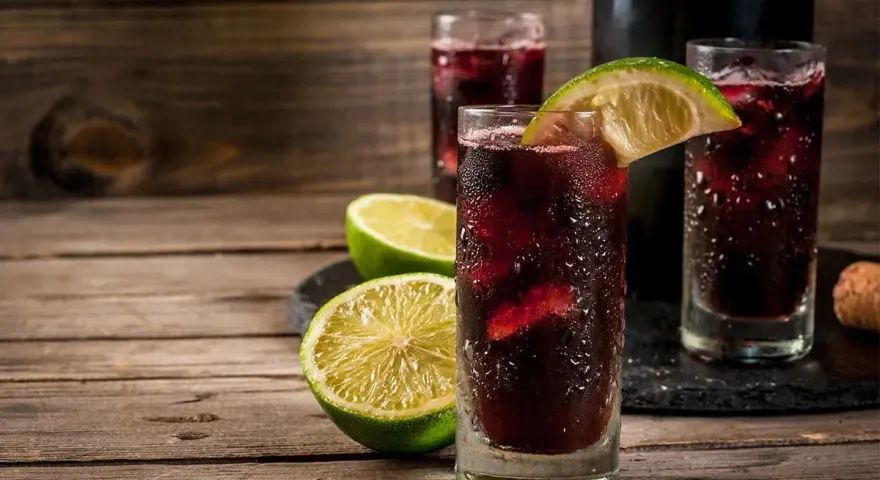 Orzeźwiający hiszpański napój alkoholowy z lodem i limonką, podany w szklankach na drewnianym stole.