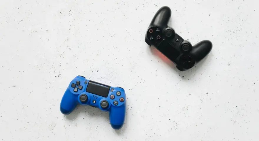 Dos mandos de videojuego, uno azul y otro negro, listos para una intensa sesión de videojuego de acción y aventura.