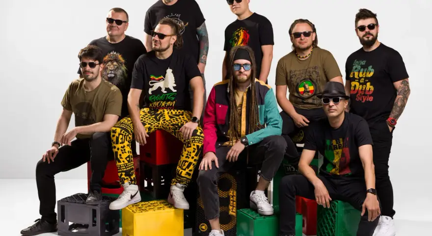 Grupa mężczyzn w koszulkach z motywami nawiązującymi do rastafarianizmu. Jeden z nich ma dredy i kolorową kurtkę, co może kojarzyć się z tym, czym jest rastafarianizm.