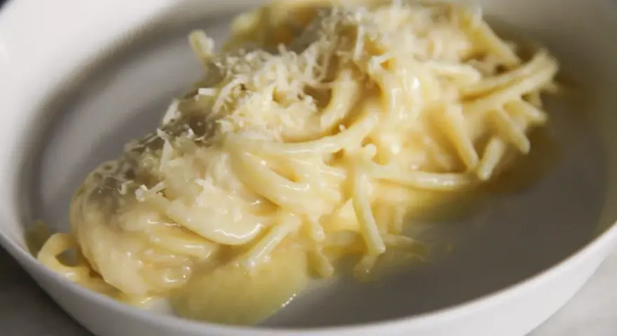 Un piatto di pasta burro e parmigiano, cremoso e invitante, con una spolverata di formaggio grattugiato.