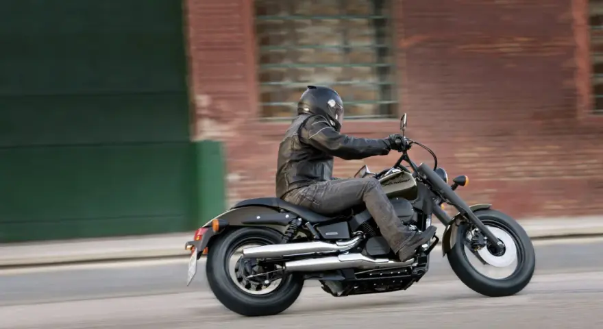 Motocyklista na Honda Shadow 750, z uwzględnieniem danych technicznych, pędzi ulicą.