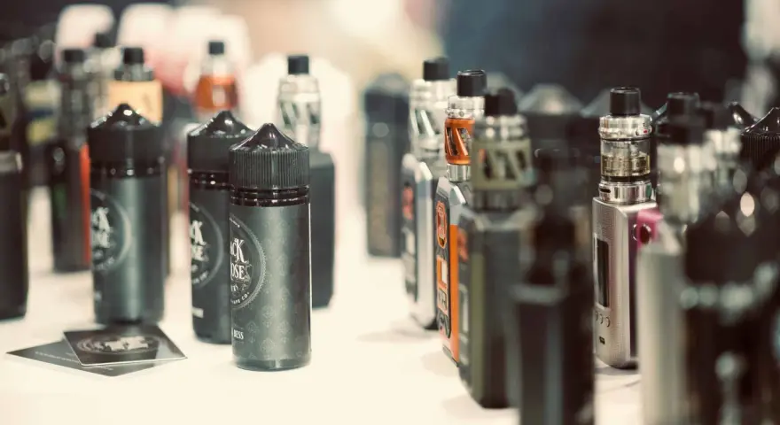 Botellas de líquidos para vapear, con diversos potenciadores de sabor, y dispositivos electrónicos en exhibición.