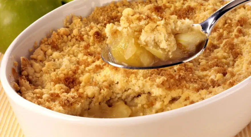 Une cuillère de crumble aux pommes, parfait pour suivre la recette Cyril Lignac. Des pommes fondantes sous une pâte croustillante.