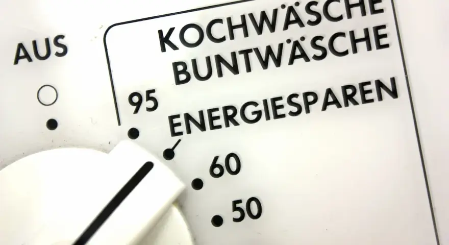 Regler einer Waschmaschine zeigt Programme wie Kochwäsche, Buntwäsche und Energiesparen. Der Wasserverbrauch hängt vom gewählten Programm ab.