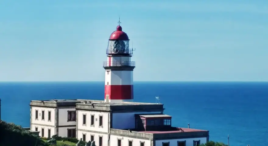 Faro blanco y rojo en la costa, un punto de referencia en la ruta de Vigo a Baiona.