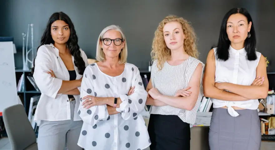 Cuatro mujeres emprendedoras, diversas en edad y etnia, posan con confianza en una oficina.