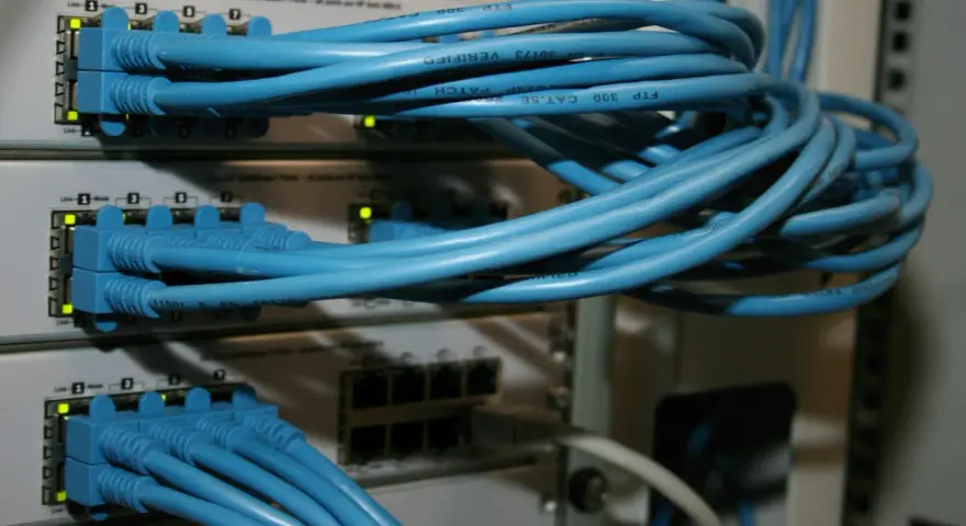 Sieć komputerowa z niebieskimi kablami Ethernet podłączonymi do przełączników. Połączenia peer to peer tworzą infrastrukturę.